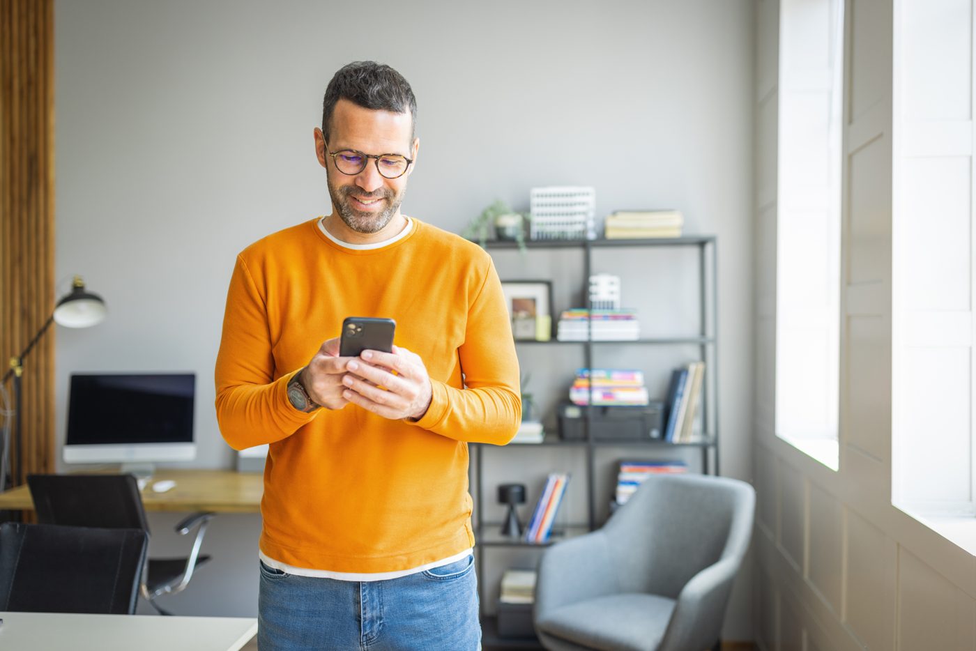 A man smiling while reading on his phone